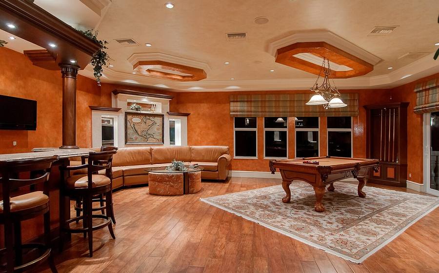 Luxury game room with a hardwood pool table under warm pendant lights