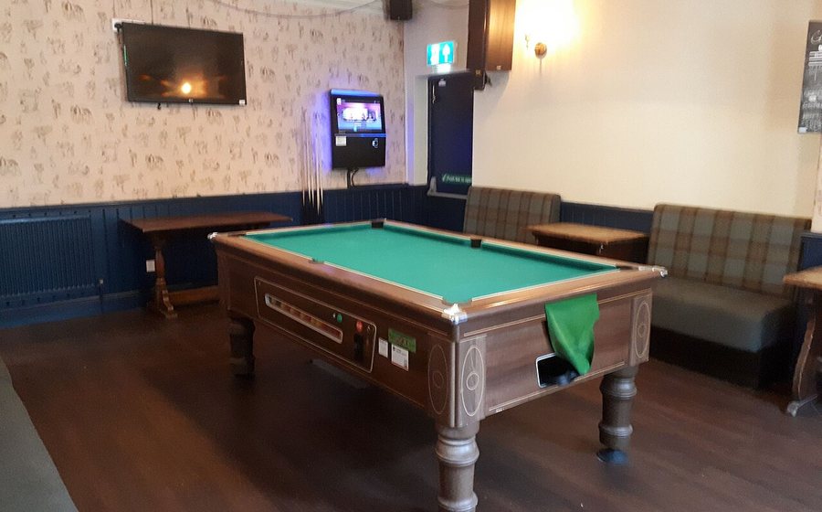 Pool table in a contemporary lounge with dark wood floors (representative photo)