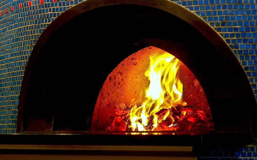 Wood fire burning inside a mosaic-tiled pizza oven (representative photo)